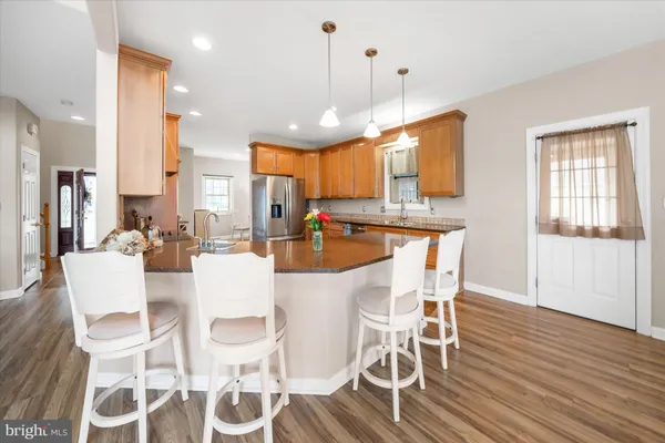 a dining room with stainless steel appliances kitchen island granite countertop a table chairs and a refrigerator