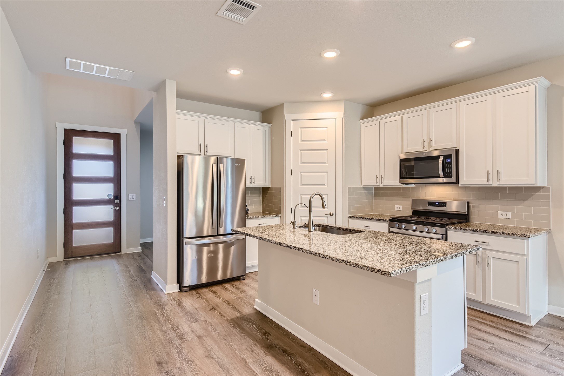 2212 Alamar Walk Leander, TX 78641 - Photo 9 of 29 a kitchen with granite countertop a refrigerator stove and microwave