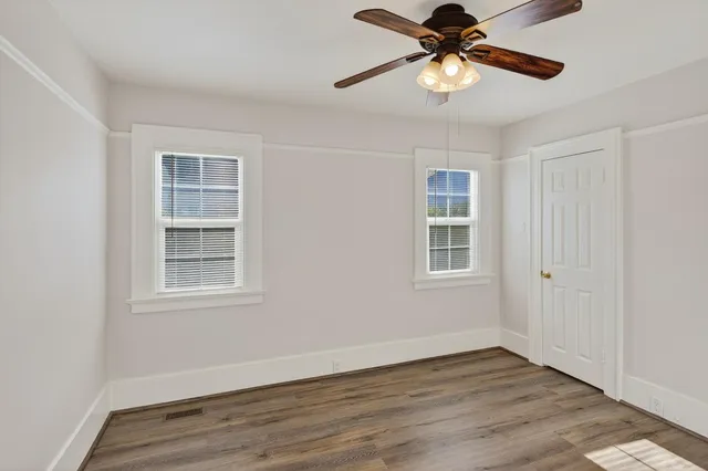 a view of an empty room with window and wooden floor