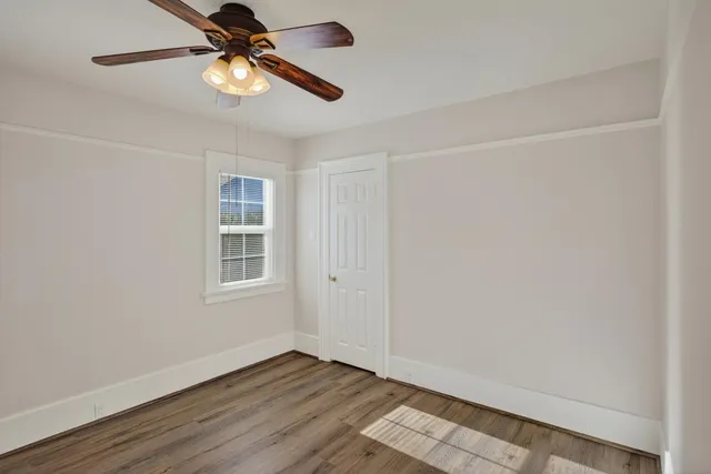 a view of an empty room with a window and wooden floor