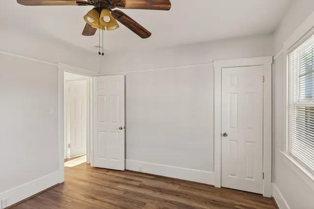 a view of an empty room with wooden floor and window