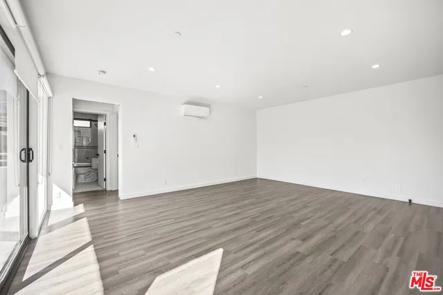a view of an empty room with wooden floor and a bathroom