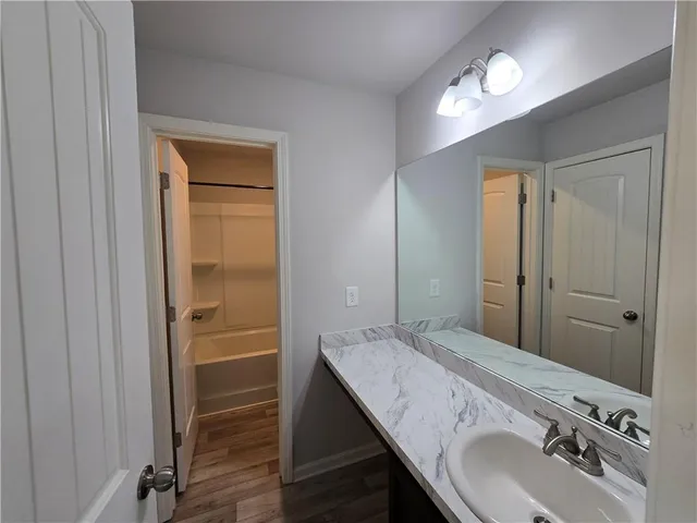 a bathroom with a granite countertop sink a mirror and a shower