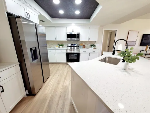 a kitchen with granite countertop a refrigerator stove and sink