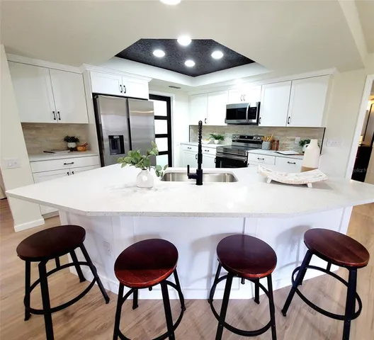 a kitchen with stainless steel appliances a dining table chairs refrigerator and microwave