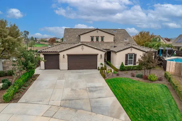 an aerial view of a house with a swimming pool a yard and a fountain