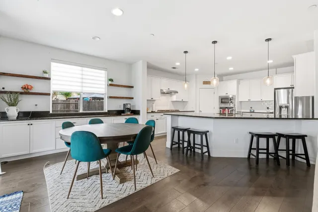 a kitchen with a dining table chairs and white cabinets