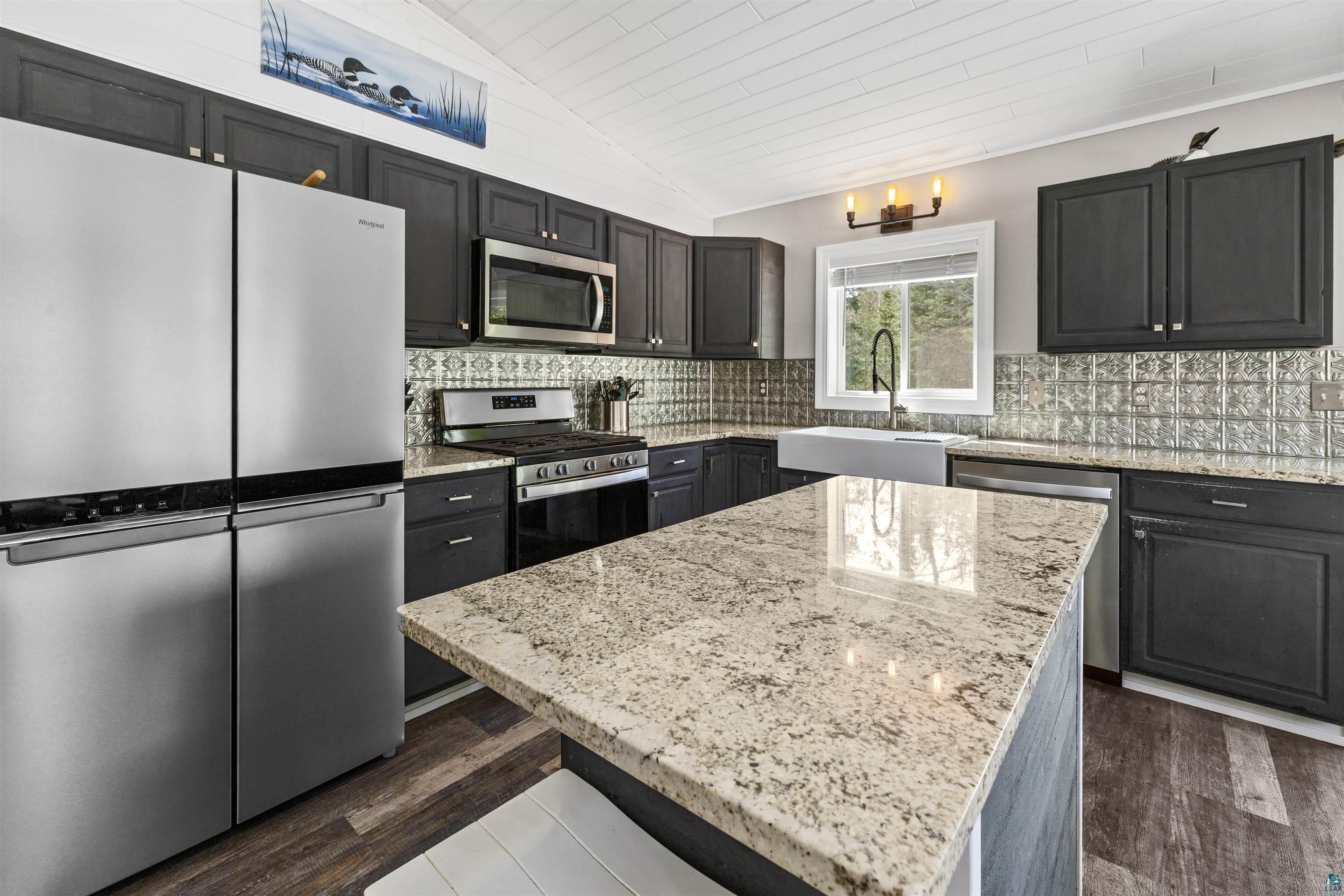13462 Villa Road Ely, MN 55731 - Photo 3 of 68 Kitchen with stainless steel appliances, Lifeproof flooring, vaulted ceiling, granite countertops, and tasteful backsplash