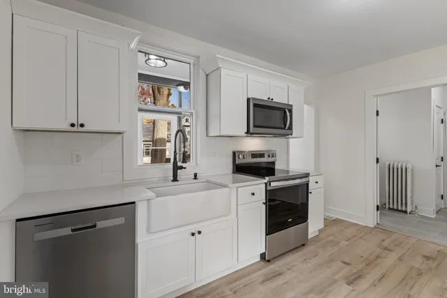 a kitchen with cabinets stainless steel appliances and wooden floor