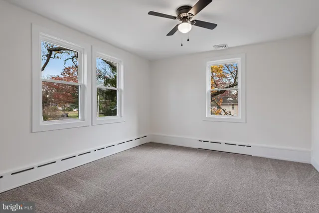 an empty room with windows and ceiling fan