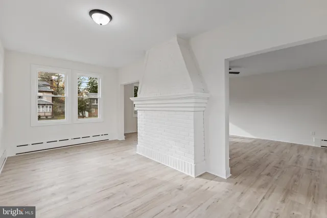 an empty room with wooden floor cabinet and windows