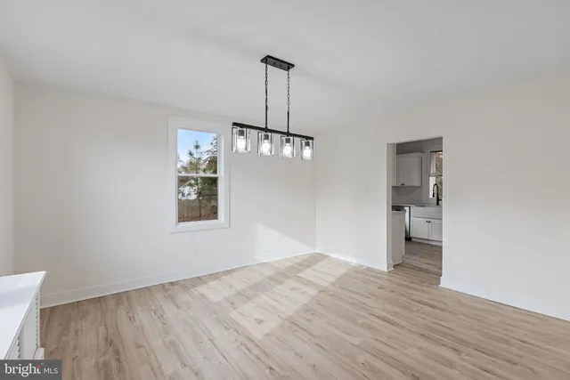 a view of an empty room with wooden floor and windows