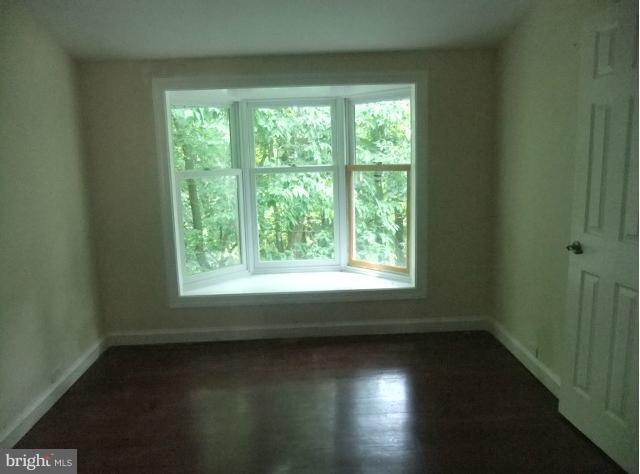 4210 Clarkdale Road Baltimore, MD 21209 - Photo 3 of 9 an empty room with wooden floor and windows