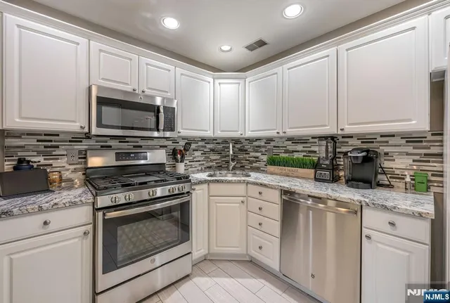 a kitchen with granite countertop white cabinets white stainless steel appliances and a sink