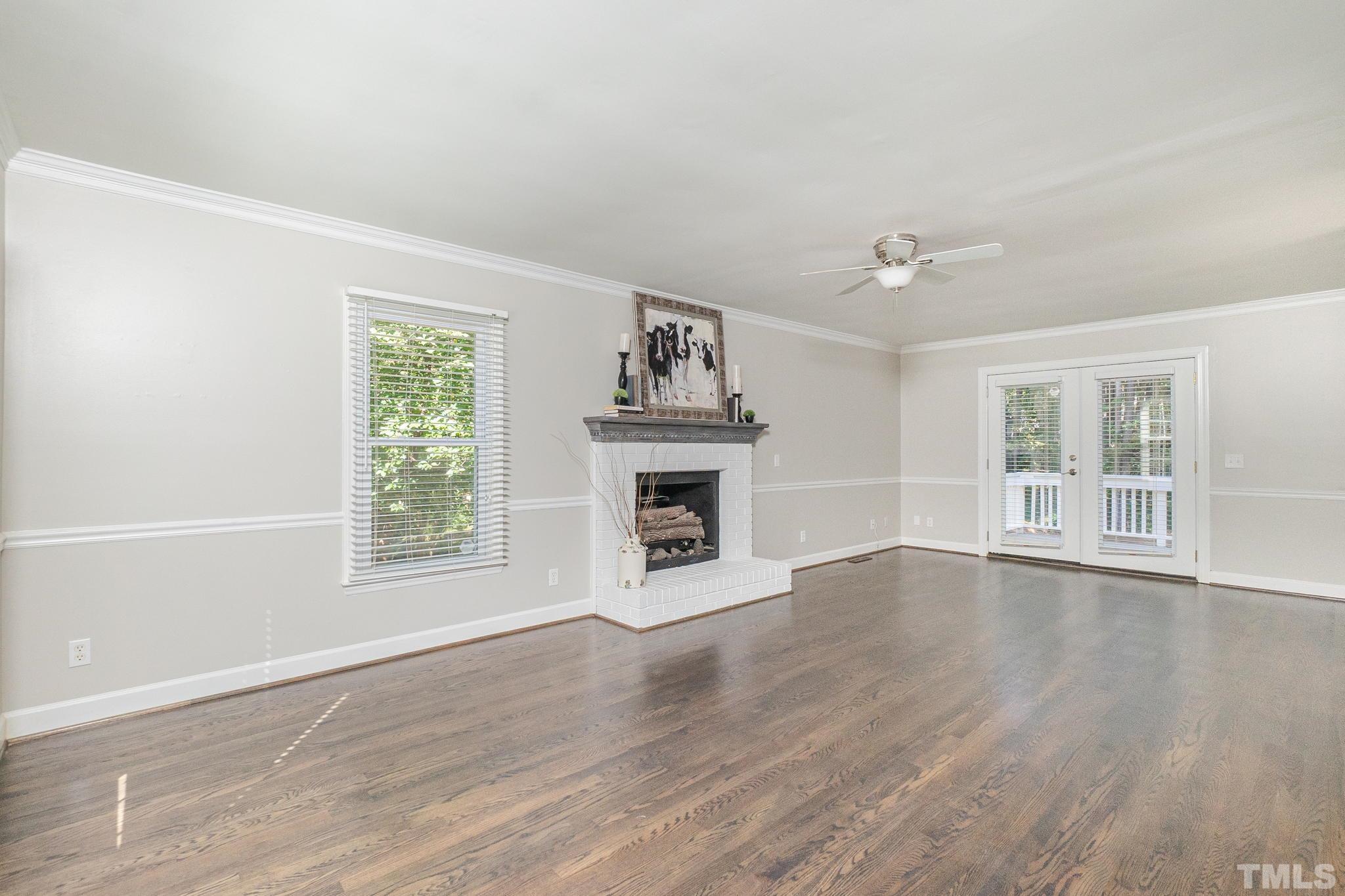 7544 Milestone Court Raleigh, NC 27615 - Photo 3 of 30 an empty room with wooden floor fireplace and windows