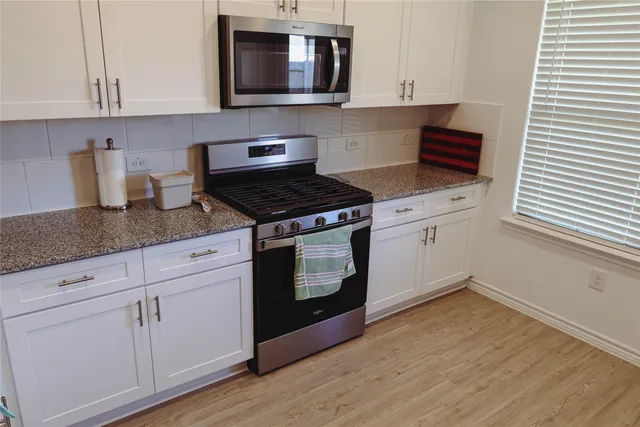 a kitchen with granite countertop cabinets stainless steel appliances and wooden floor