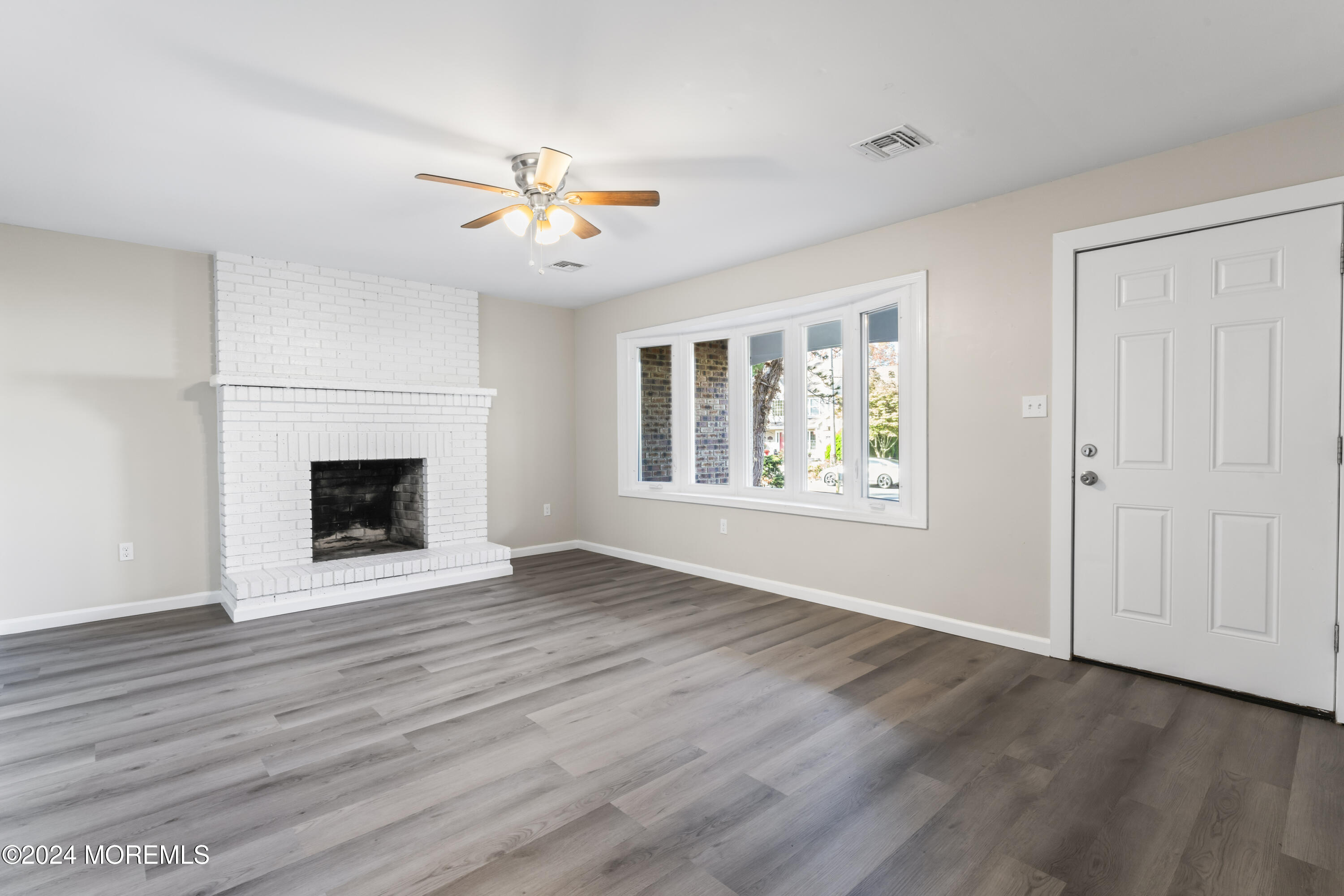 321 Float Avenue Manahawkin, NJ 08050 - Photo 2 of 31 an empty room with wooden floor fireplace and windows