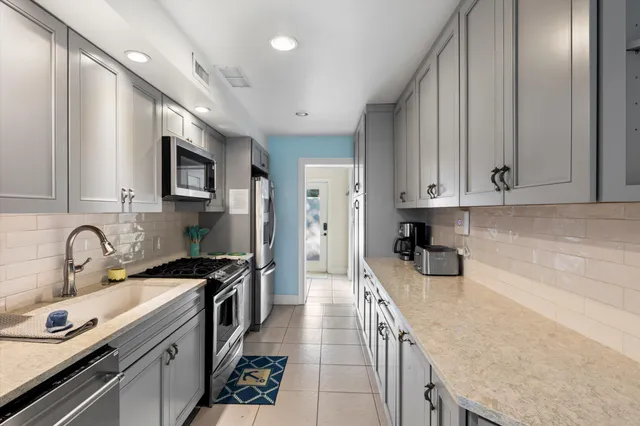 a kitchen with granite countertop a sink stainless steel appliances and cabinets