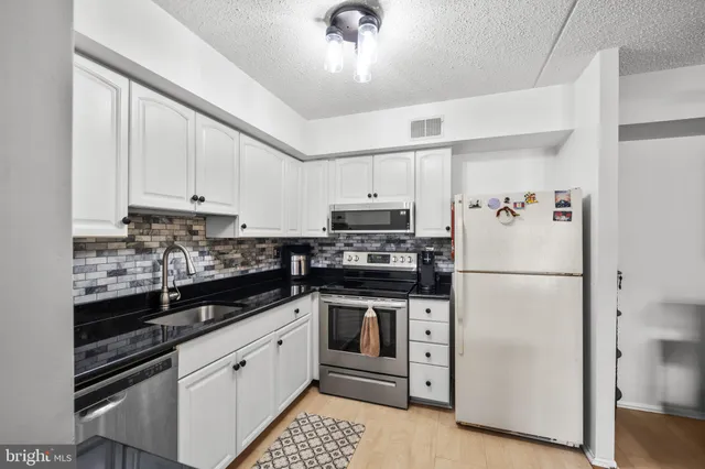 a white kitchen with stainless steel appliances and white cabinets