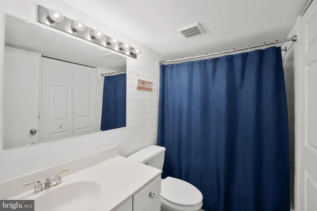 a bathroom with a sink a toilet a mirror and shower curtain