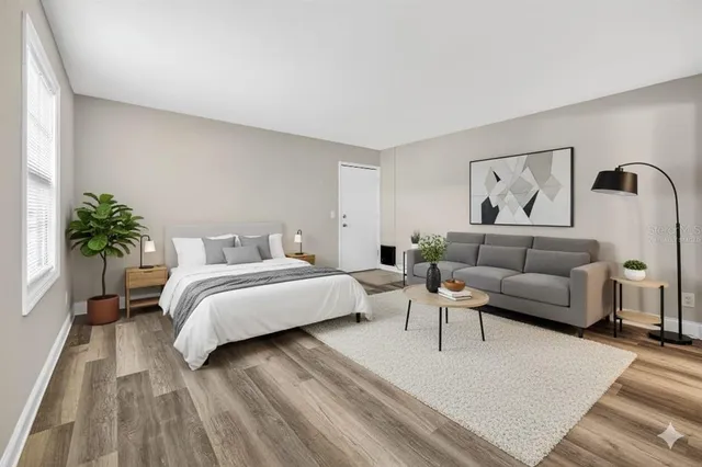 a spacious bedroom with a bed a couch and potted plant on the dresser
