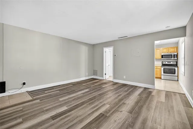 a view of an empty room with wooden floor and a window