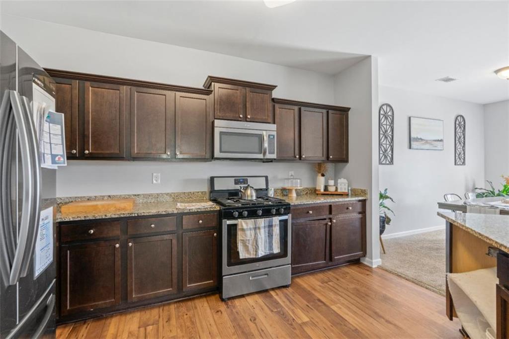 4219 Box Elder Path Gainesville, GA 30504 - Photo 15 of 35 a kitchen with stainless steel appliances granite countertop wooden cabinets a stove top oven a sink and dishwasher