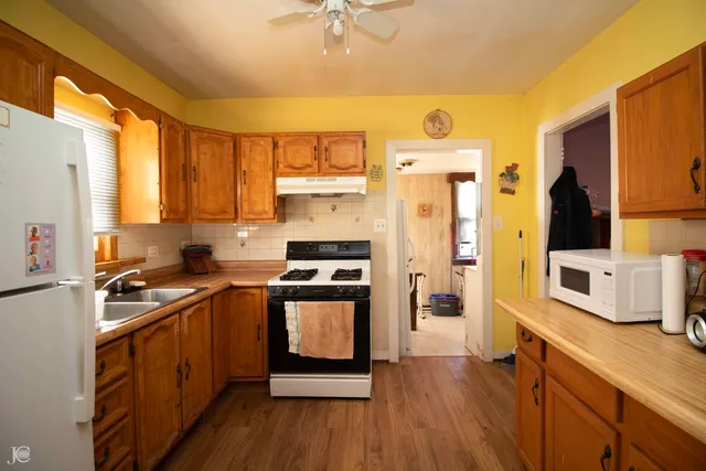 a kitchen with stainless steel appliances a stove a sink dishwasher a refrigerator white cabinets and wooden floor