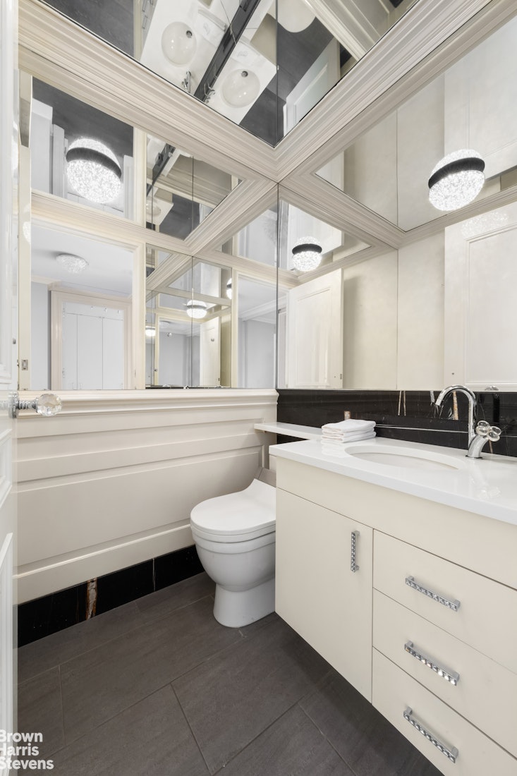 200 East 69th Street, Unit 47 Manhattan, NY 10021 - Photo 16 of 29 a bathroom with a toilet a sink and a large mirror