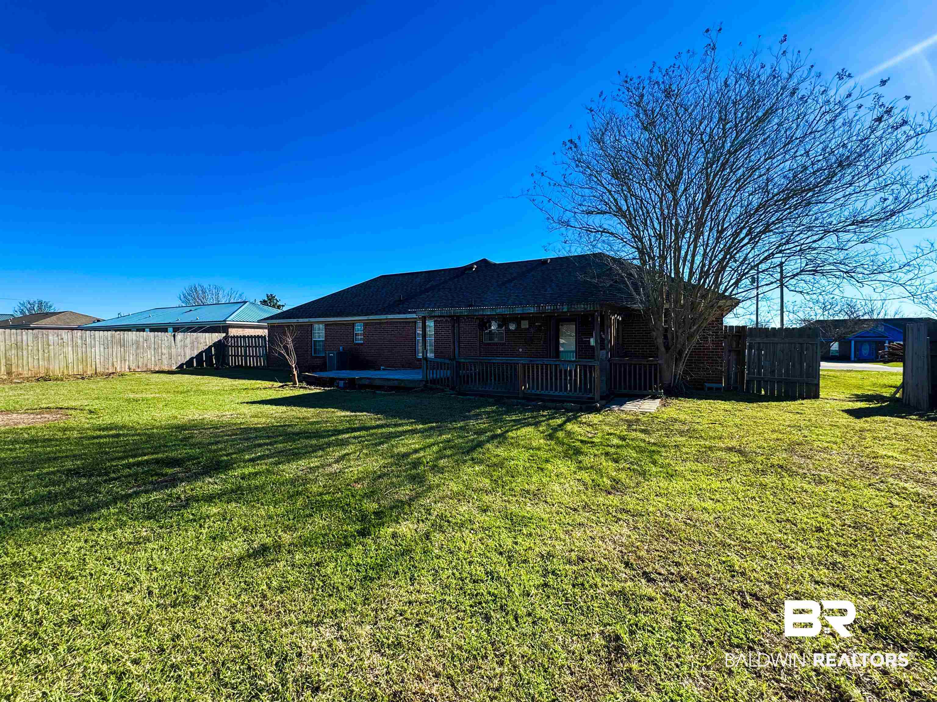 Rear view of house with brick siding, a fenced backyard, and a yard