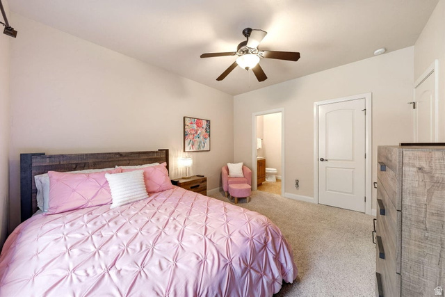 1609 East 10 S Street St. George, UT 84790 - Photo 43 of 68 Carpeted bedroom featuring a rustic wood headboard, ceiling fan with integrated lighting, and direct access to an adjacent bathroom with wood-finish vanity