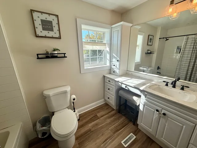 a bathroom with a granite countertop toilet a sink and a mirror
