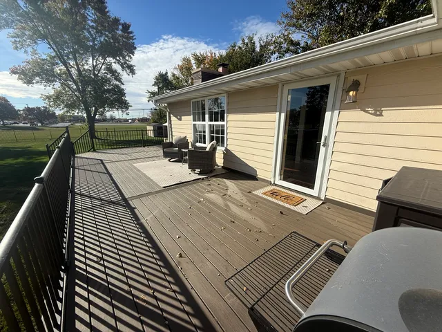 a view of a patio with table and chairs with wooden floor and fence