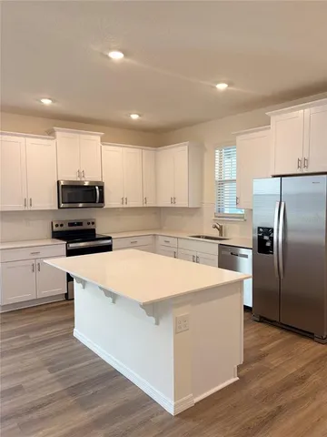 a kitchen with a sink a microwave a refrigerator and cabinets