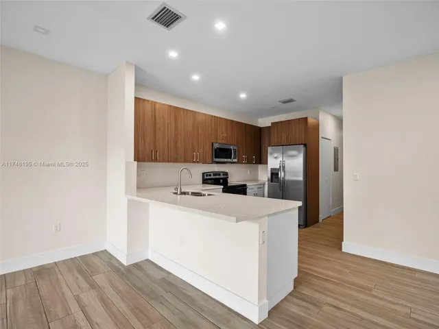 a kitchen with a sink a microwave a refrigerator and cabinets
