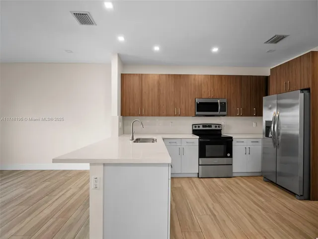 a view of kitchen with stainless steel appliances granite countertop refrigerator sink and stove