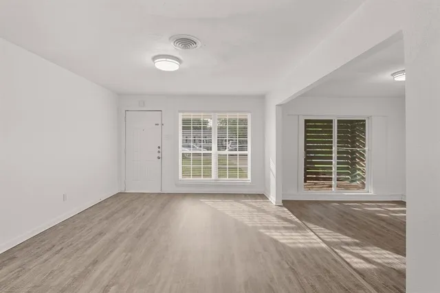 a view of an empty room with a window and wooden floor