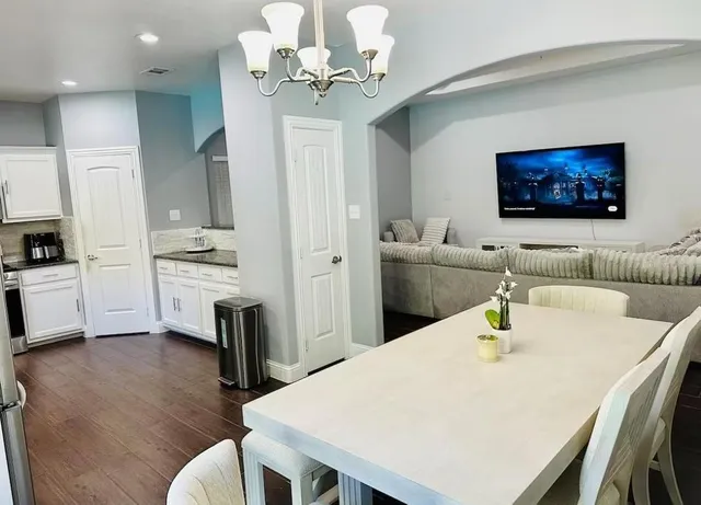 a living room with stainless steel appliances furniture a chandelier and a dining room