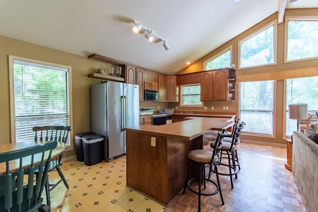 a kitchen with stainless steel appliances granite countertop a stove a refrigerator a kitchen island a table and chairs