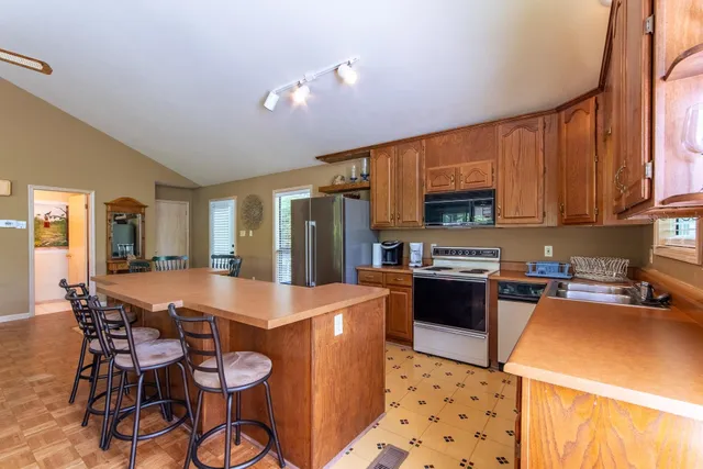 a kitchen with granite countertop a refrigerator a stove a sink dishwasher and white cabinets with wooden floor