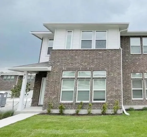 a living room with stainless steel appliances wooden floors and kitchen view