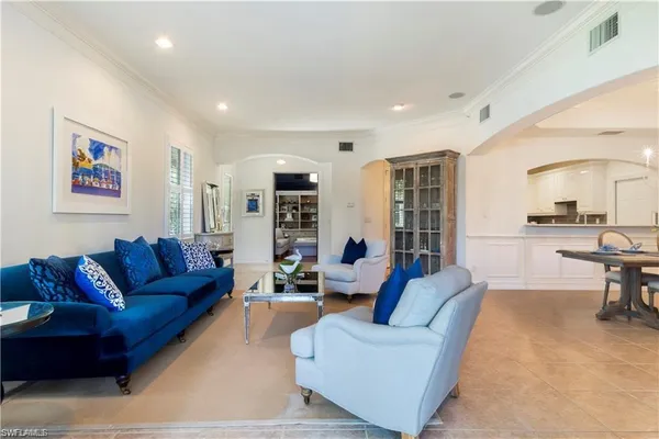 a living room with furniture kitchen view and a large window