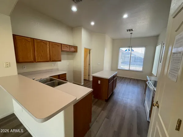 a kitchen with granite countertop a stove a sink a refrigerator and wooden floor