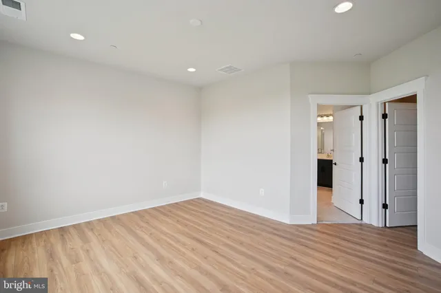 a view of an empty room with wooden floor and closet