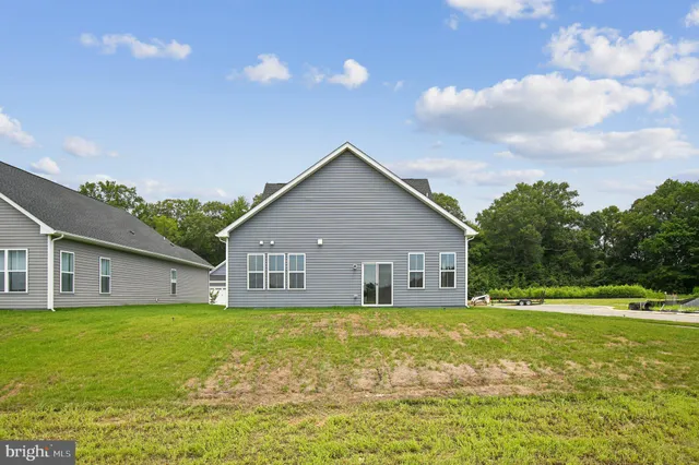 a view of a house next to a big yard and large trees
