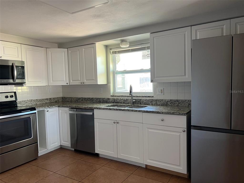 7835 Arbordale Drive Port Richey, FL 34668 - Photo 6 of 21 a kitchen with granite countertop white cabinets white stainless steel appliances and a sink