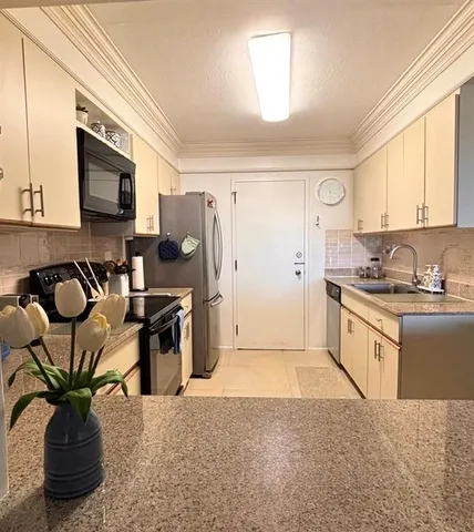 a kitchen with stainless steel appliances granite countertop a refrigerator a sink a stove a counter space and cabinets