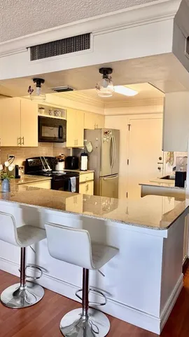 a living room with stainless steel appliances kitchen island granite countertop a couch and a view of living room