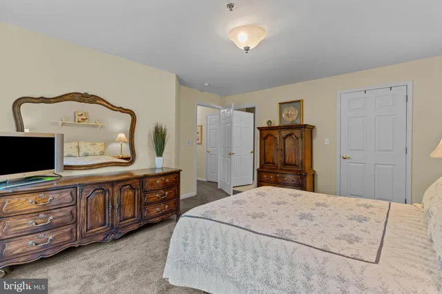 a large bedroom with a bed and a flat tv screen on dresser