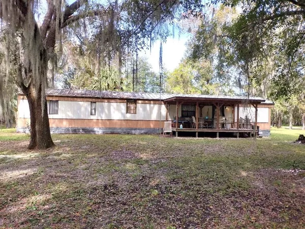 a view of backyard with large trees and wooden fence